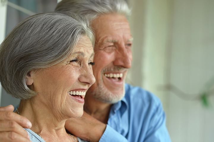 A couple smiling after getting full mouth dental implants..