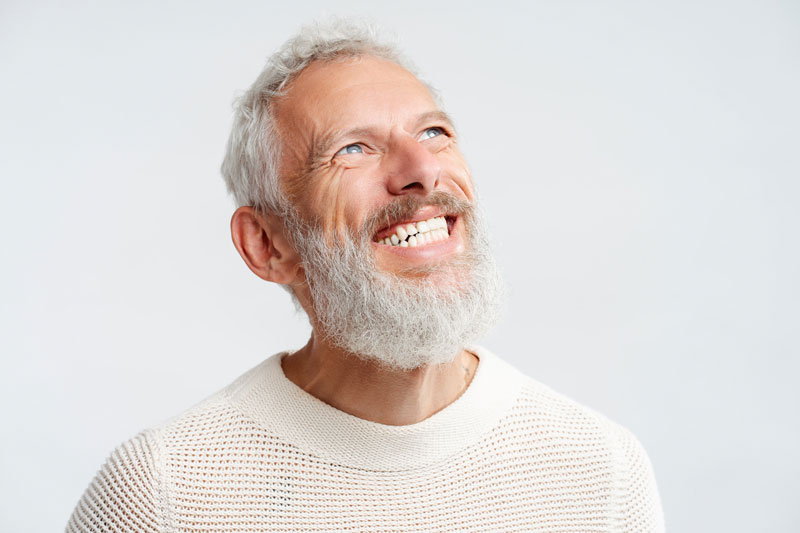 Portrait smiling handsome Scandinavian man with white teeth looking up isolated on white background. Health care, dental treatment concept