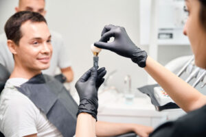 Dental professional examines tooth model and X-ray to assess patient condition and treatment options