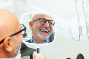 happy patient smiling with a mirrior in hand, dental office